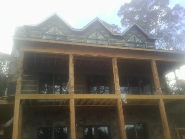 Dormers and porch framing on a large log home under construction — Roof Coating work by our crew in Ada