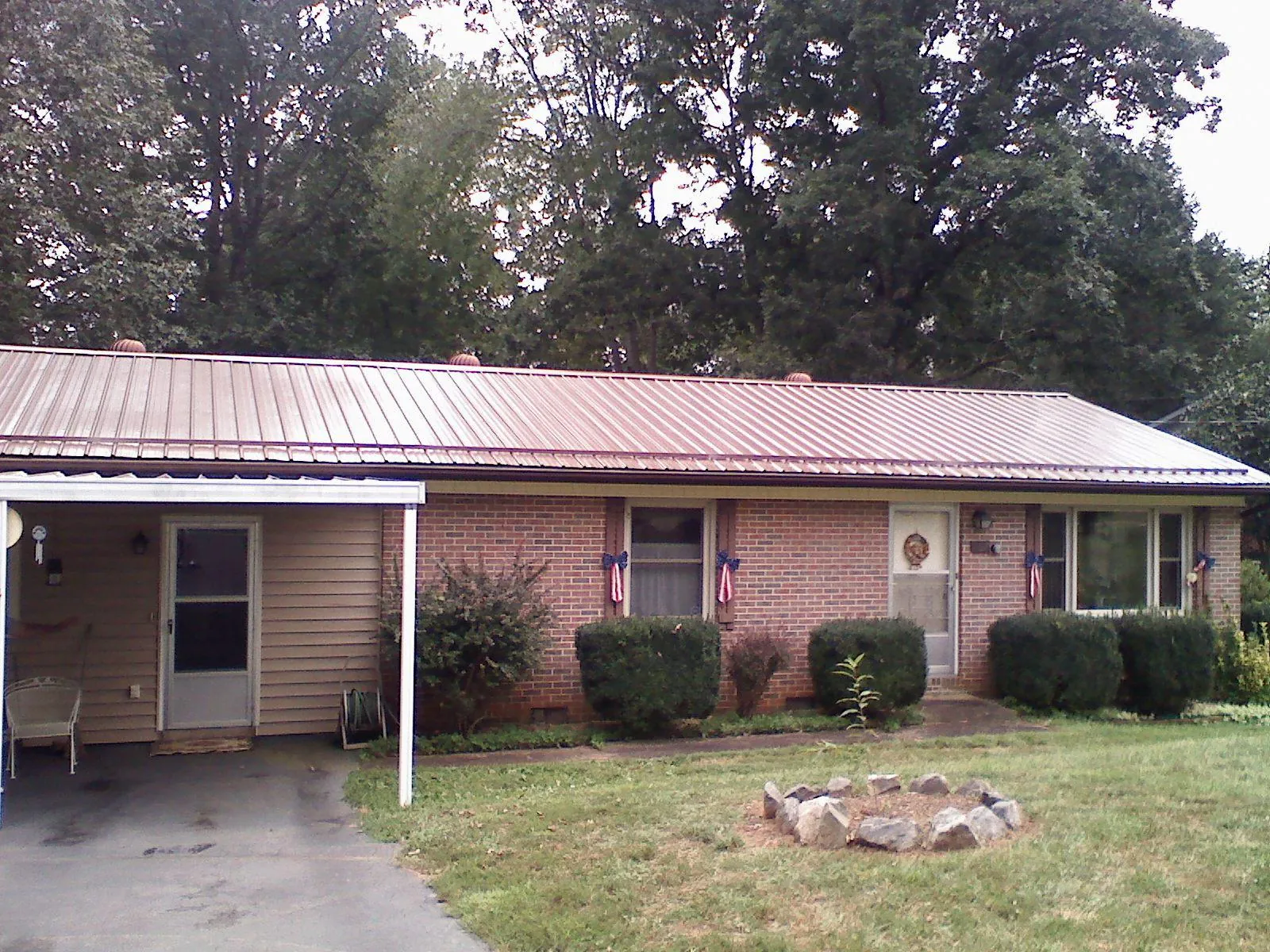 Bronze metal roof and carport on a brick ranch home — Roof Repair work by our crew in Ada